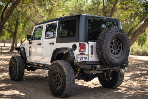 White 2007-2018 Jeep JK 4-Door with DV8 Square Back Hard Top parked on a dirt road surrounded by trees.