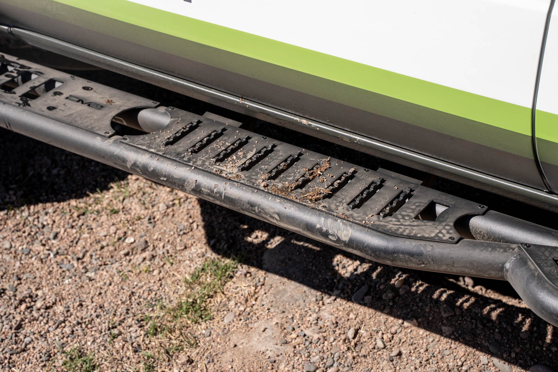 Close-up of a Tacoma side step with a gravel surface.