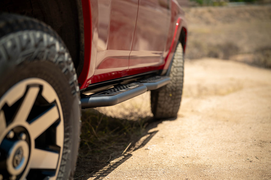 Close-up of a red 4runner side with a focus on the tire on a dirt road.