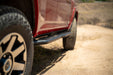 Close-up of a red 4runner side with a focus on the tire on a dirt road.