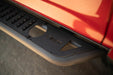 Close-up of a car's side step with a brand logo on a red vehicle.