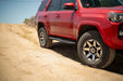 Red SUV driving on a dirt road with a clear sky