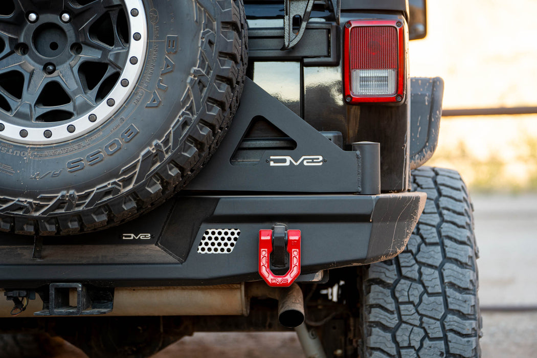 Close-up of a Jeep with a DV8 bumper and tire carrier, set against a blurred natural background.