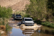 Ford Bronco vehicles driving through a river in a desert setting with the competition series front bumper.