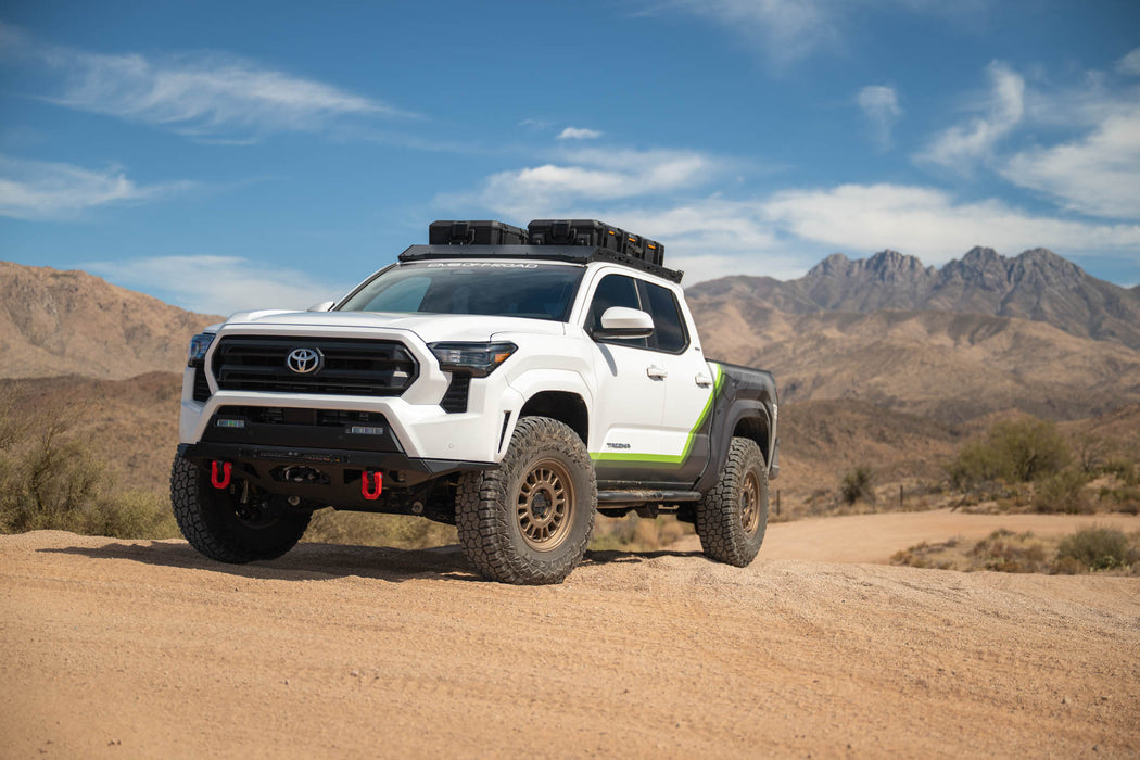 Toyota Tacoma with DV8 off road parts on a dirt road with mountains in the background