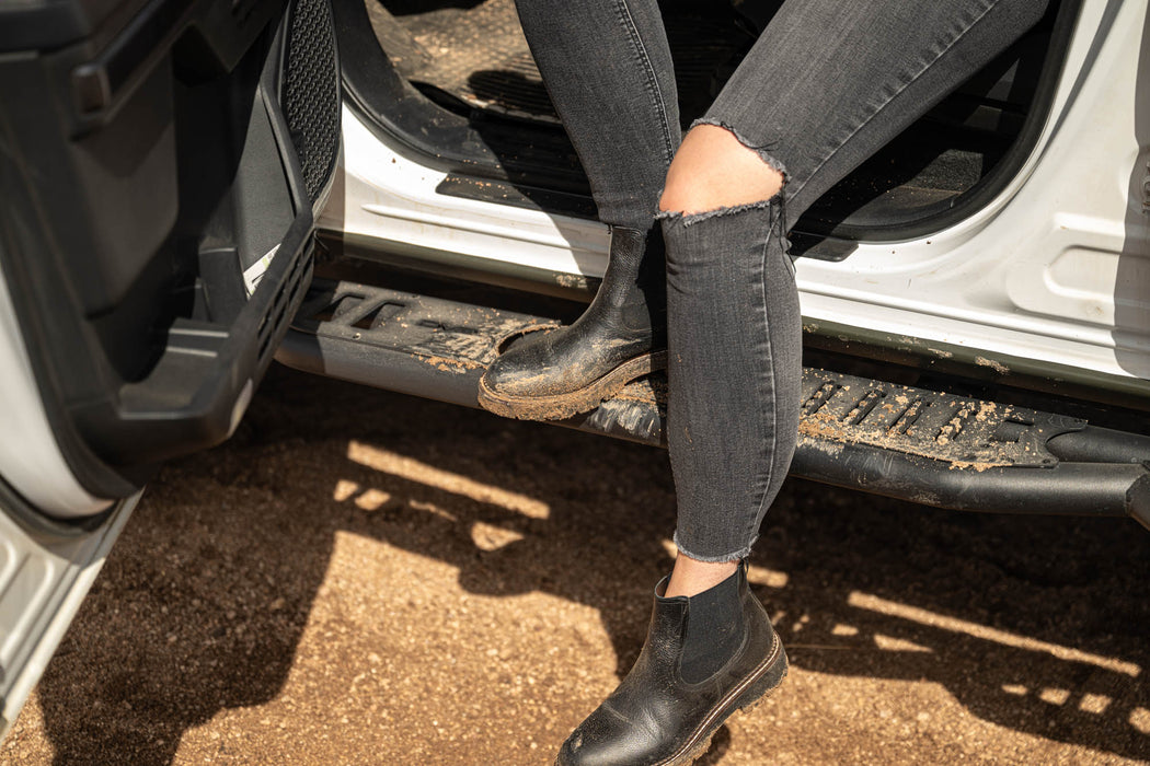 Person stepping out of a vehicle with off road side steps wearing black shoes and jeans.